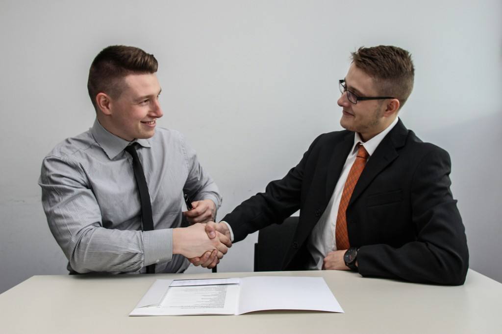 Two colleagues shaking hands across a meeting table